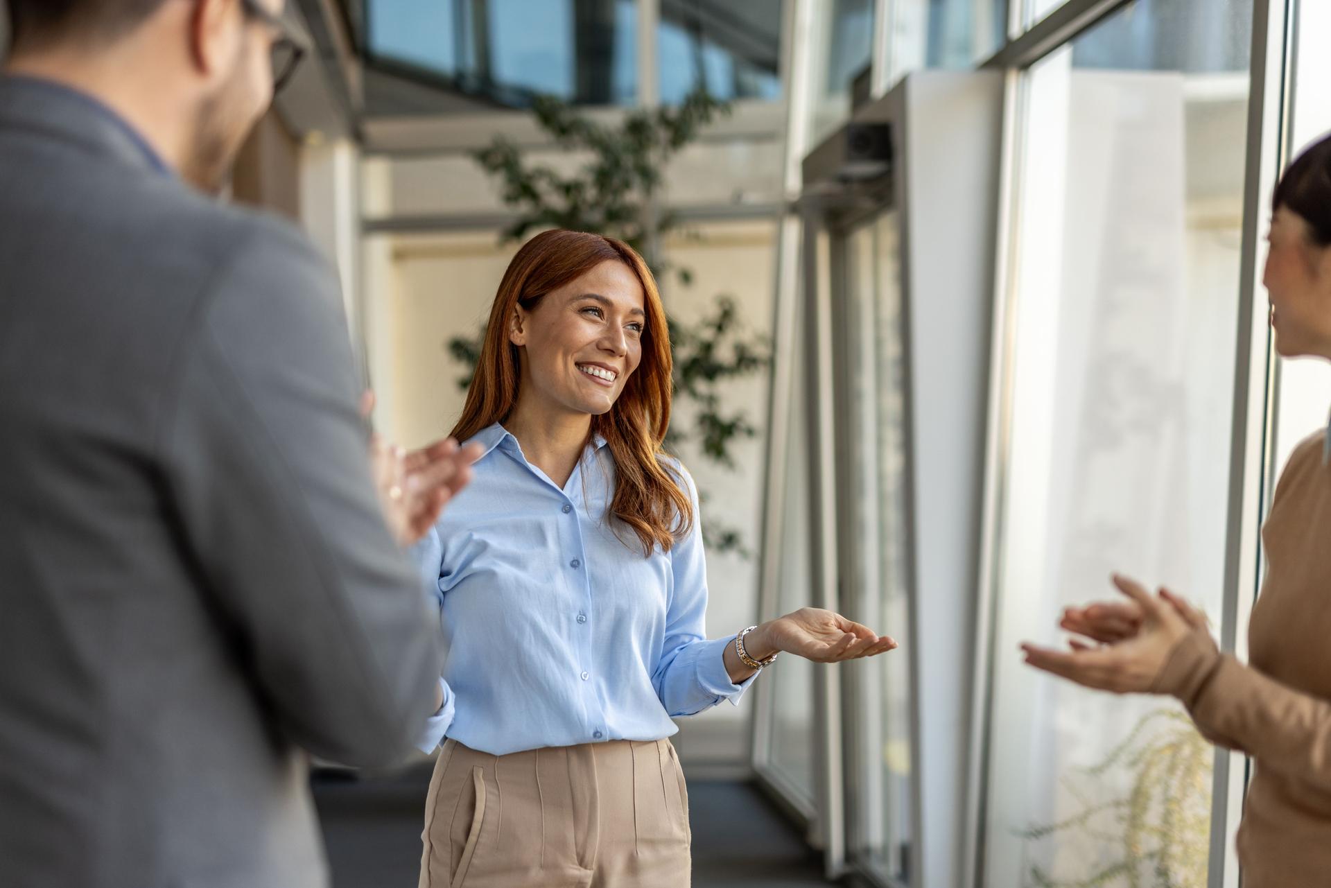 Businesswoman receiving congratulations from colleagues in office hallway